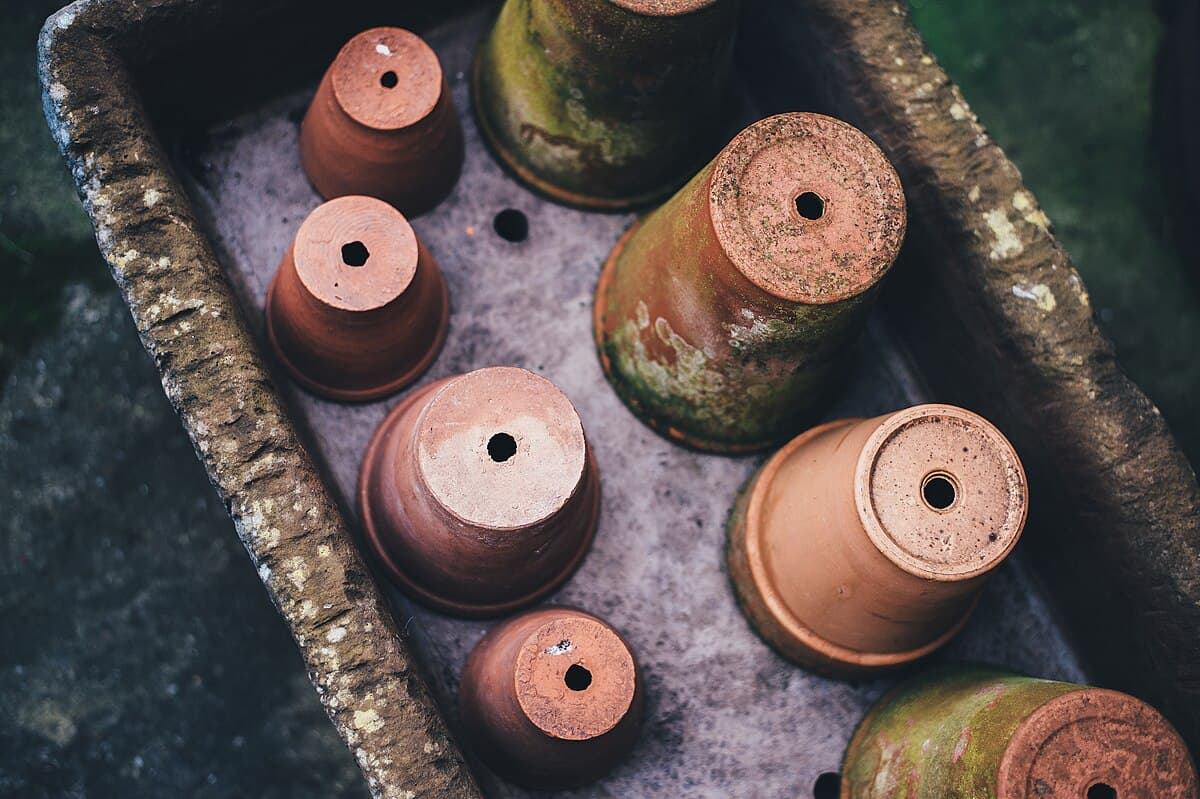 A row of terracotta clay pots of various sizes on a garden surface